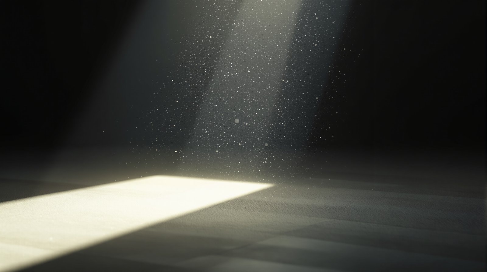 Fine dust particles drifting in a single beam of sunlight crossing a dim, empty room