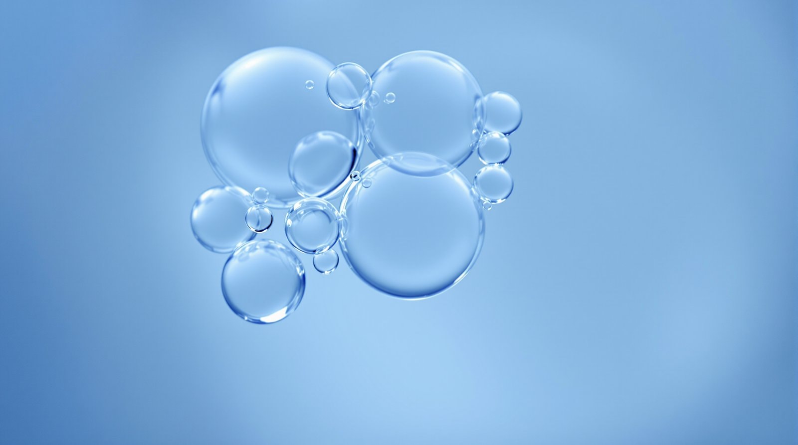 A cluster of translucent bubble-like spheres of different sizes floating in clear blue water